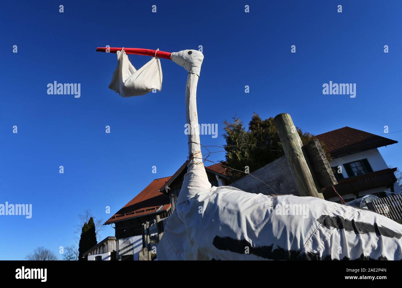 Buching, Allemagne. 06 Dec, 2019. Une cigogne maison figure avec un sac dans son bec symbolise la naissance d'un bébé en face d'une ferme. Credit : Karl-Josef Opim/dpa/Alamy Live News Banque D'Images