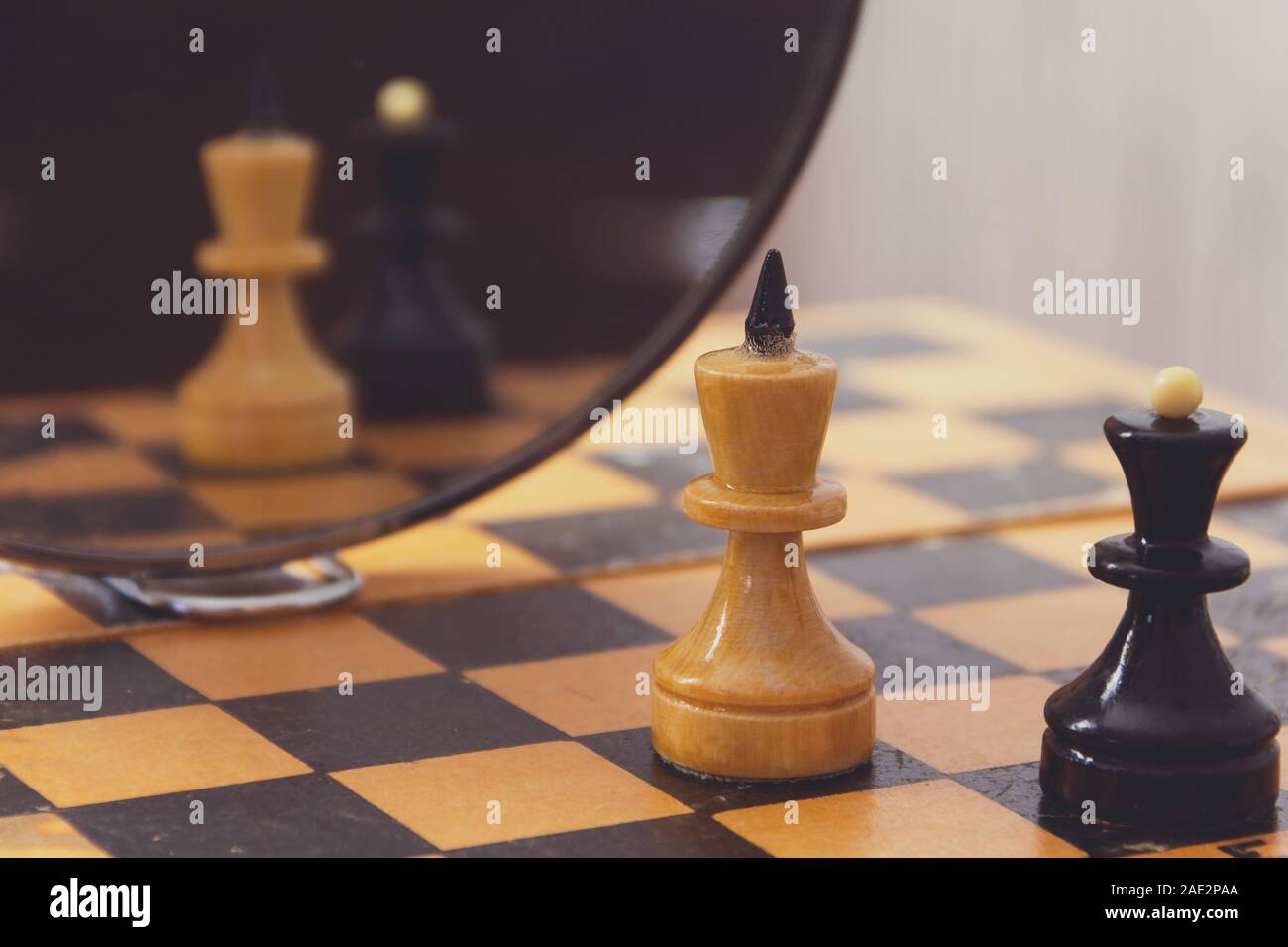 Deux pièces d'échecs le roi et la reine sur l'échiquier et leur reflet dans le miroir. Banque D'Images