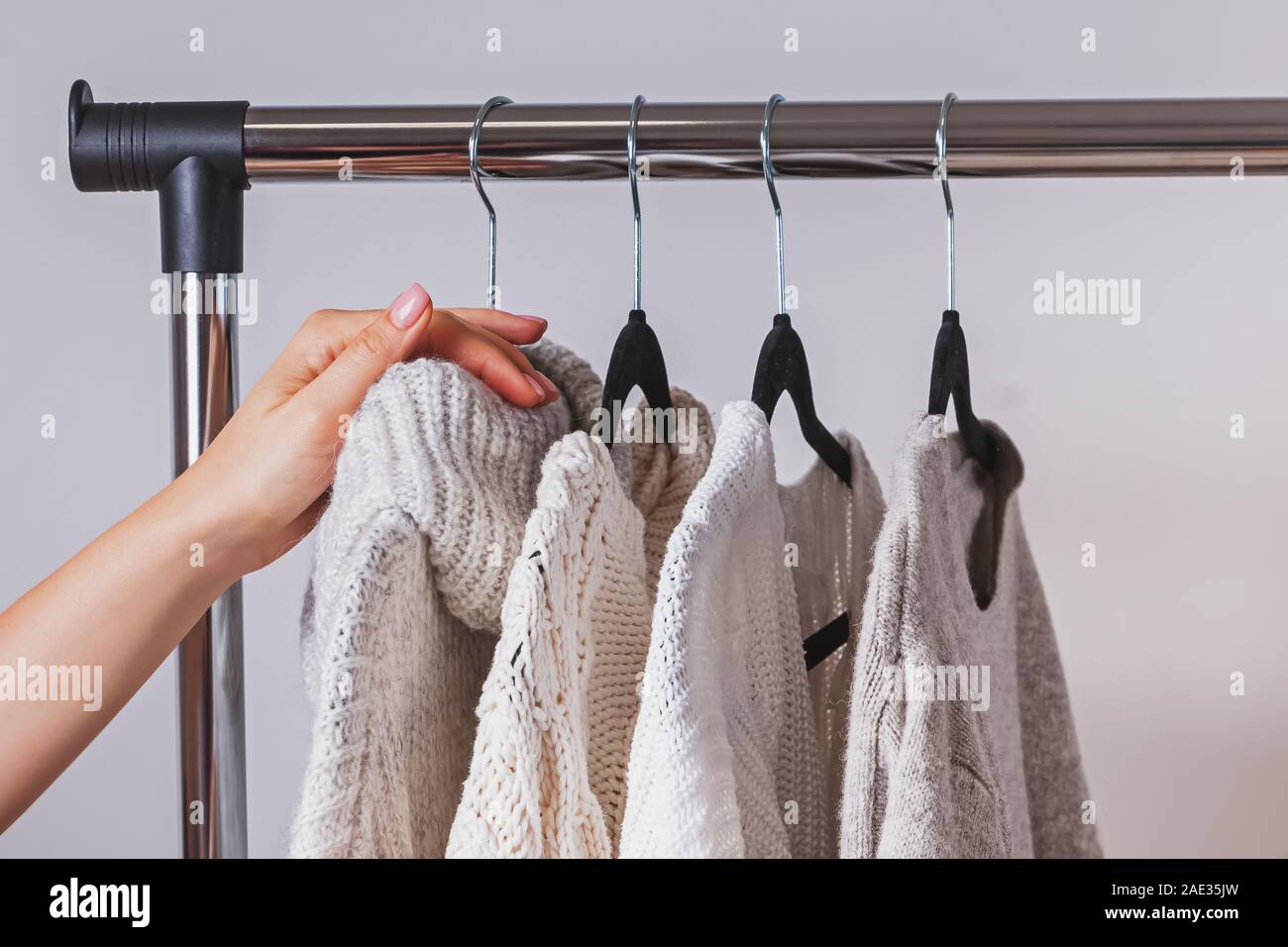 La main de la femme de choisir l'un des pulls du porte-manteau Banque D'Images