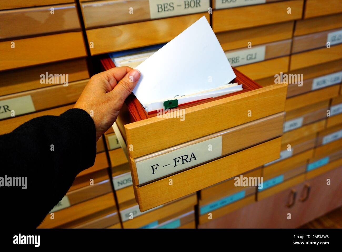 Meubles à tiroirs en bois boîtes et lettre f imprimé sur l'une d'elle et une main tenant un feuillet catalogue Banque D'Images