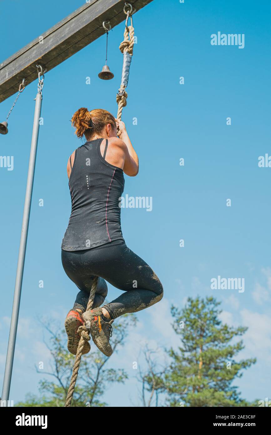 Athletic young girl climbing sur la corde. La participation au jeu des sports de plein air en été. Vertical image Banque D'Images