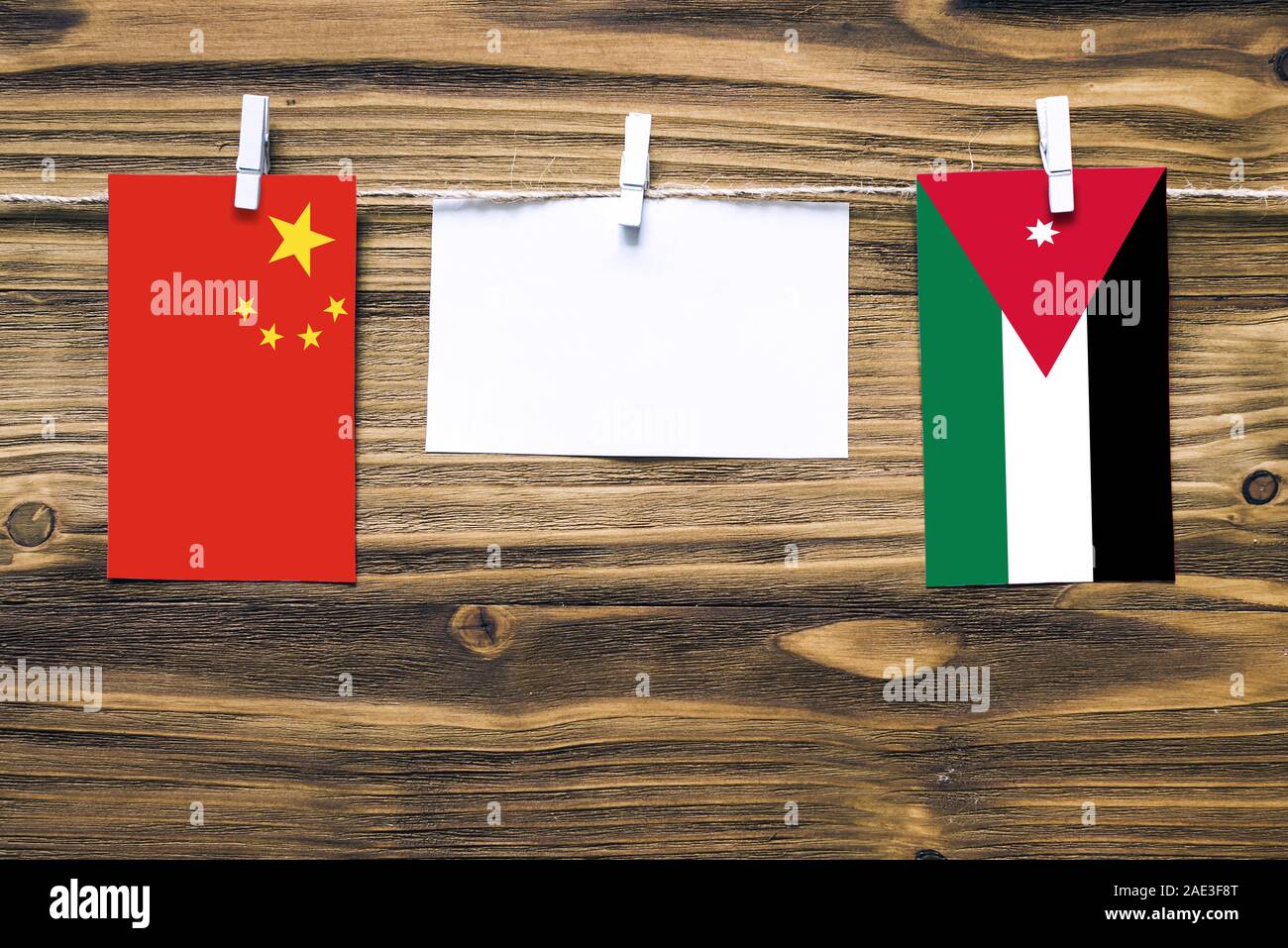 Drapeaux suspendus de Chine et la Jordanie attaché à la corde avec des pinces à linge avec de l'espace de copie sur papier blanc sur fond de bois.Les relations diplomatiques bet Banque D'Images