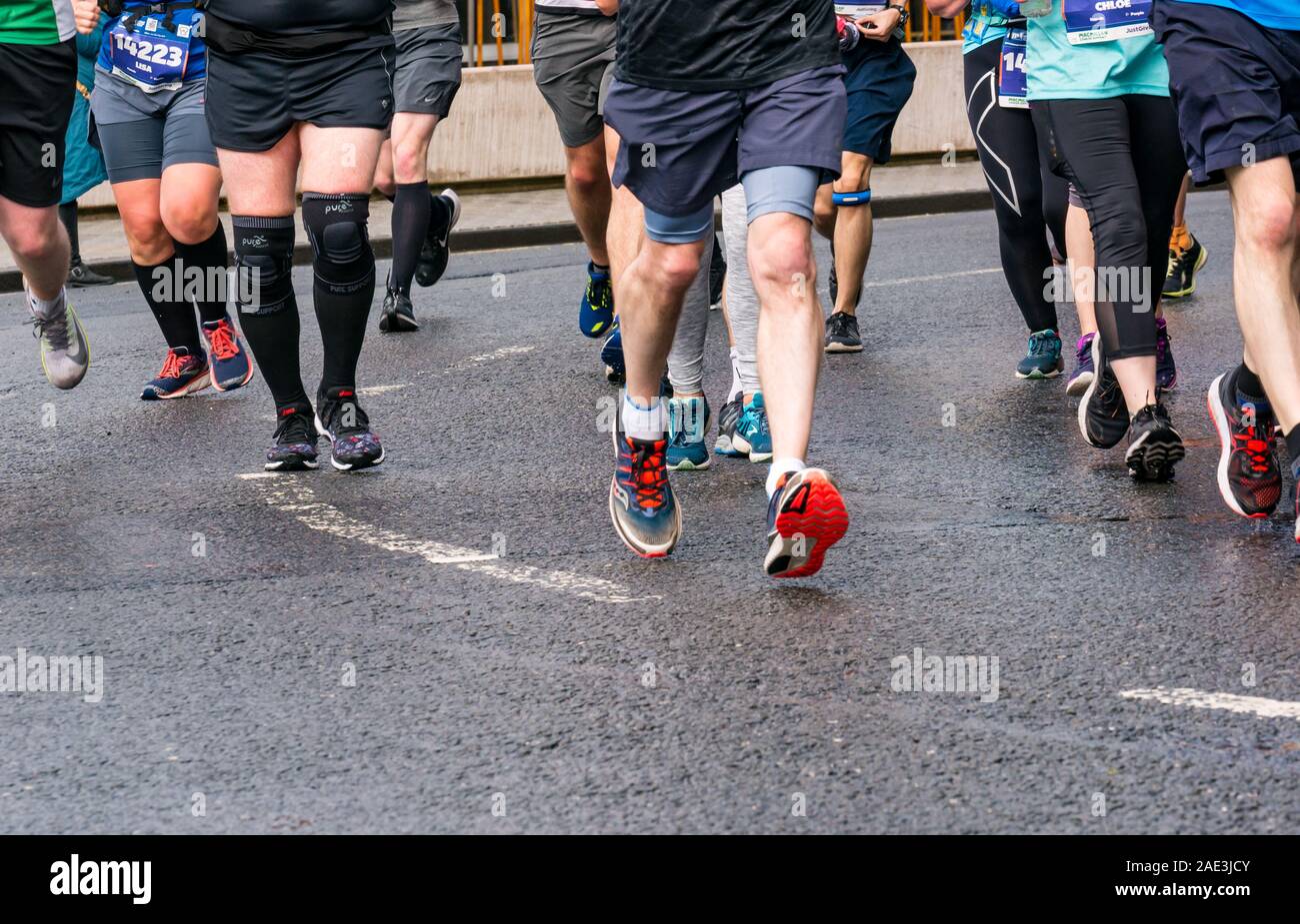 Close up porteur jambes pieds & chaussures de course sur piste mouillée, Edinburgh Festival Marathon 2019, Ecosse, Royaume-Uni Banque D'Images