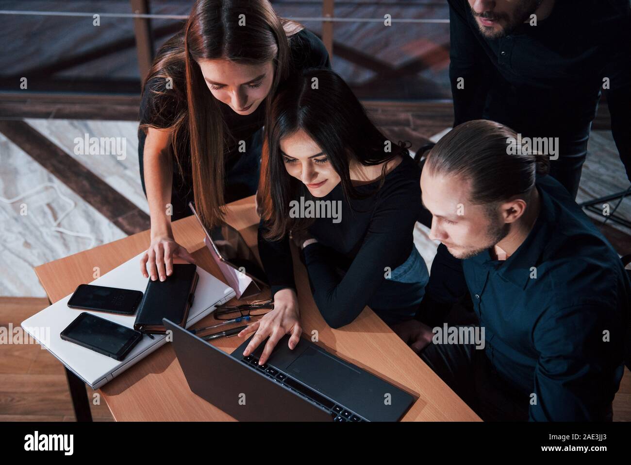 Le défilement des documents sur ordinateur portable. De jeunes gens d'affaires de l'équipe travaille sur son projet de nuit au bureau Banque D'Images