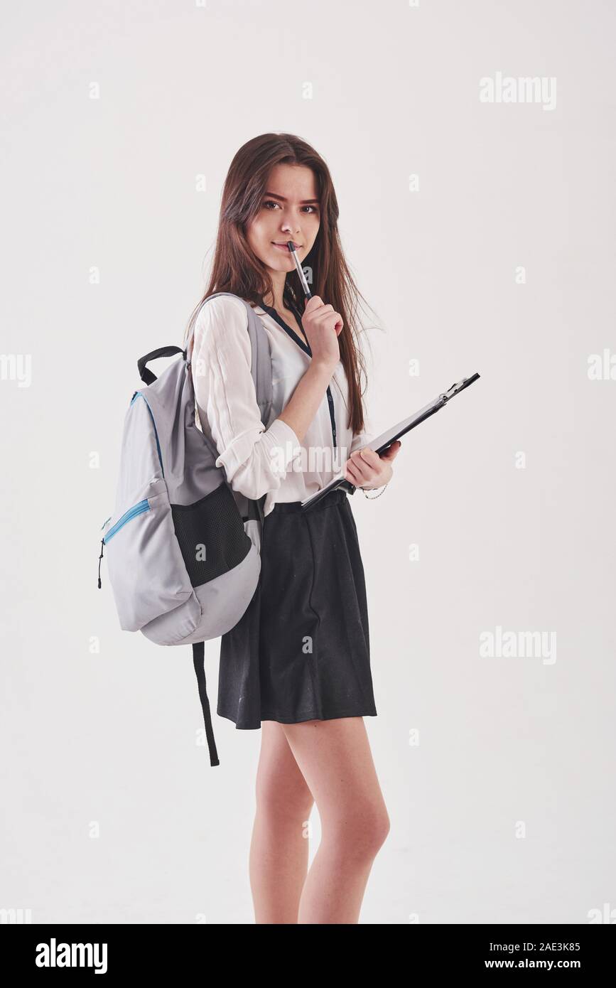 Jeune étudiante en jupe et sac à dos avec le bloc-notes dans les mains se  dresse contre fond blanc Photo Stock - Alamy