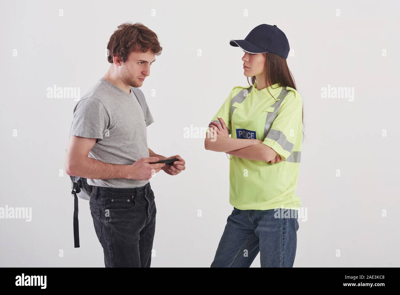 Deux personnes qui se parlaient. Pretty woman in police verte uniforme a Conversation with male student against white background dans le studio Banque D'Images