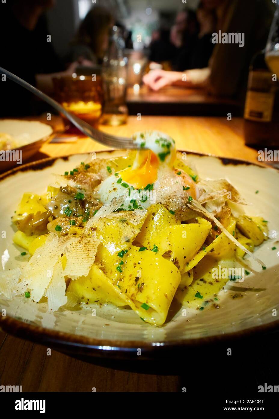 Pappardelle maison ai Funghi (champignons) avec placage avec un oeuf poché, de Parmesan et de flocons de garni de ciboulette. Banque D'Images