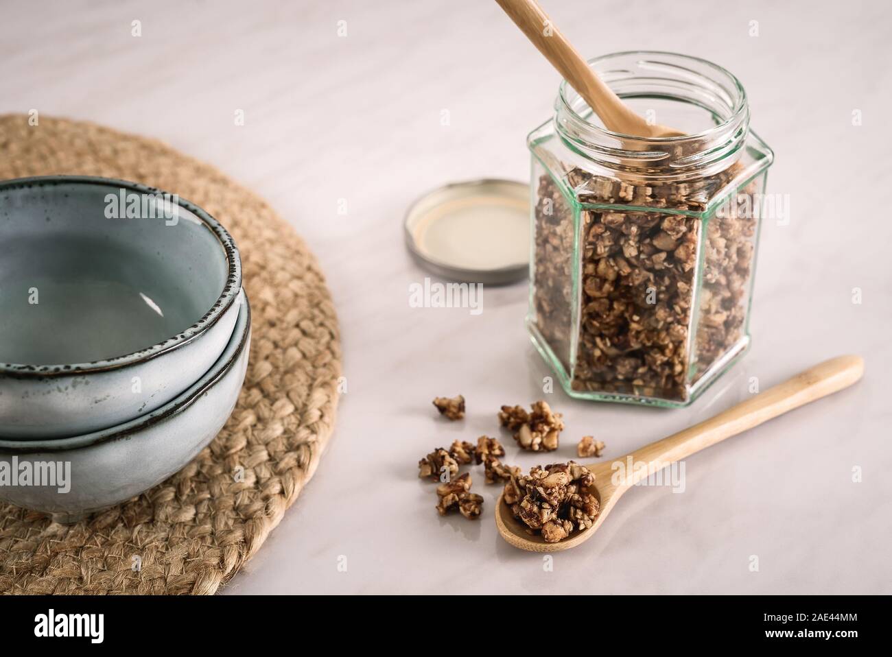 Petit-déjeuner fait maison et la valeur nutritive des céréales dans un bocal en verre et sur cuillère en bois avec des bols de céramique sur en table de cuisine dans la lumière du matin frais Banque D'Images