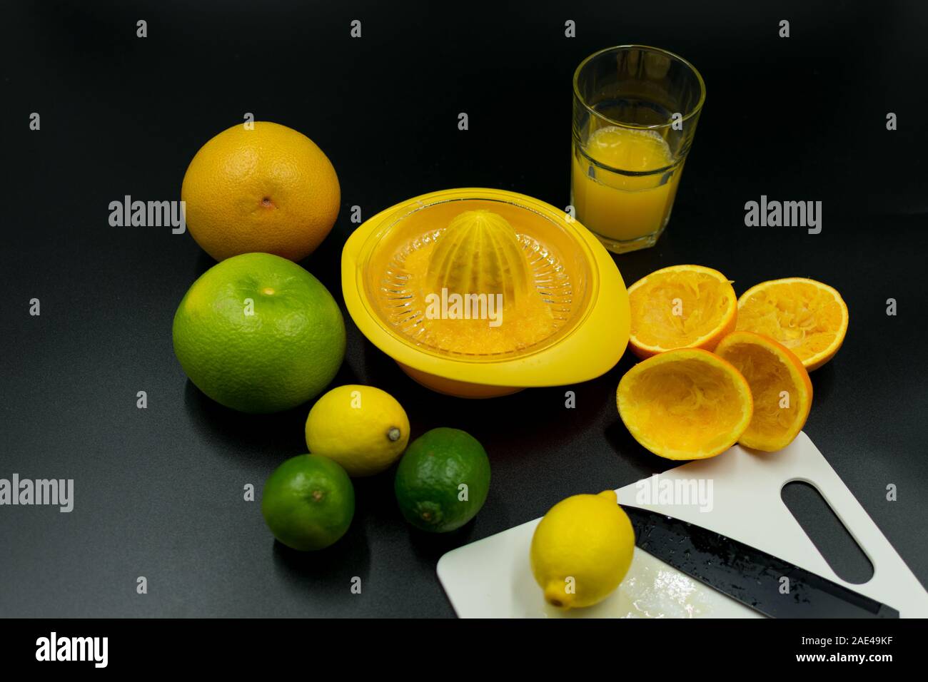 Presse-agrumes utilisés avec différents fruits, écorce d'orange et de verre. Sur fond noir Banque D'Images