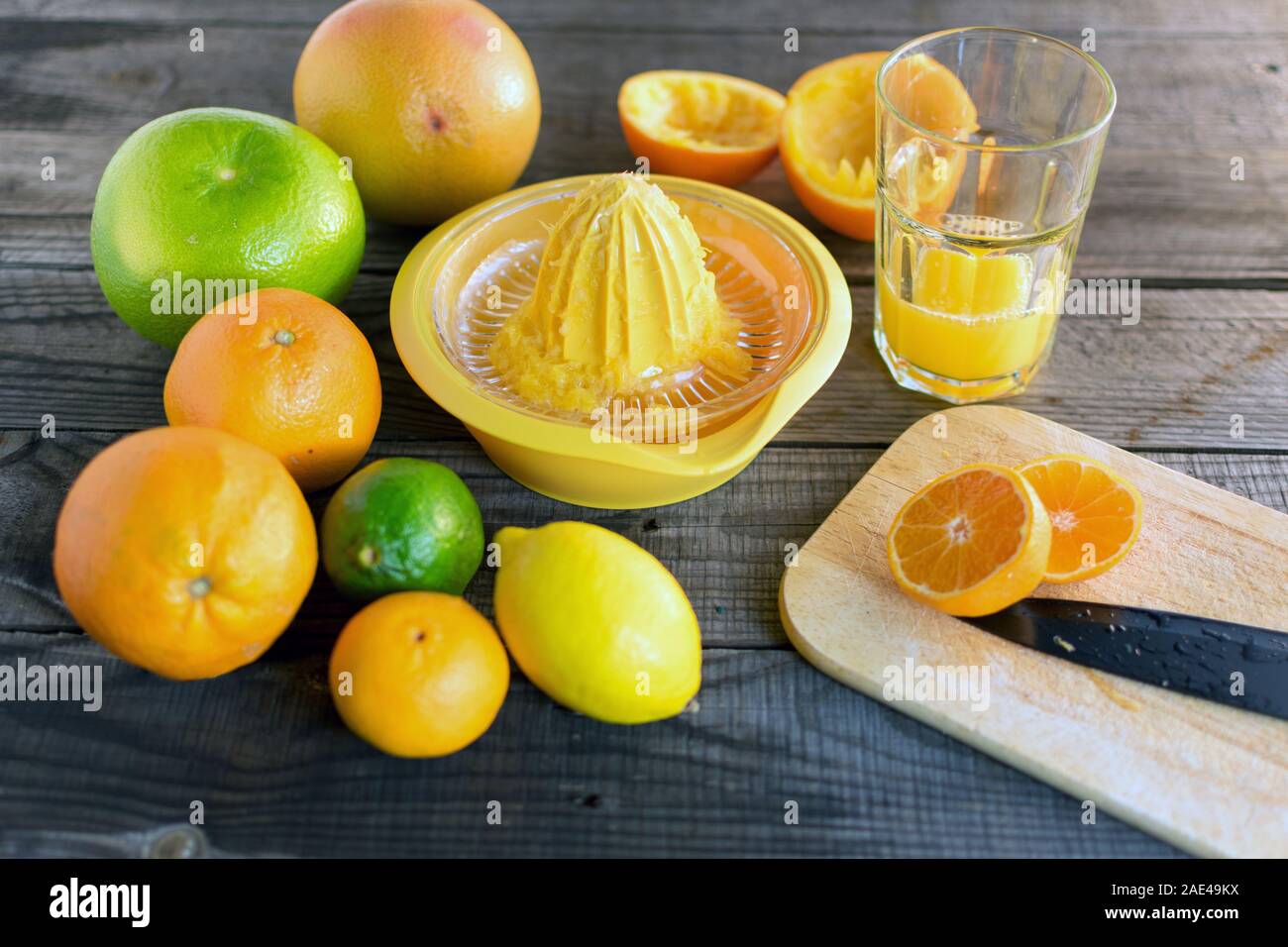 Mandarin de moitié avec divers agrumes et un presse-agrumes, couteau à découper, jus et le verre. Sur plancher en bois Banque D'Images Mandarin de moitié avec divers agrumes et un presse-agrumes, couteau à découper, jus et le verre. Sur plancher en bois Banque D'Images