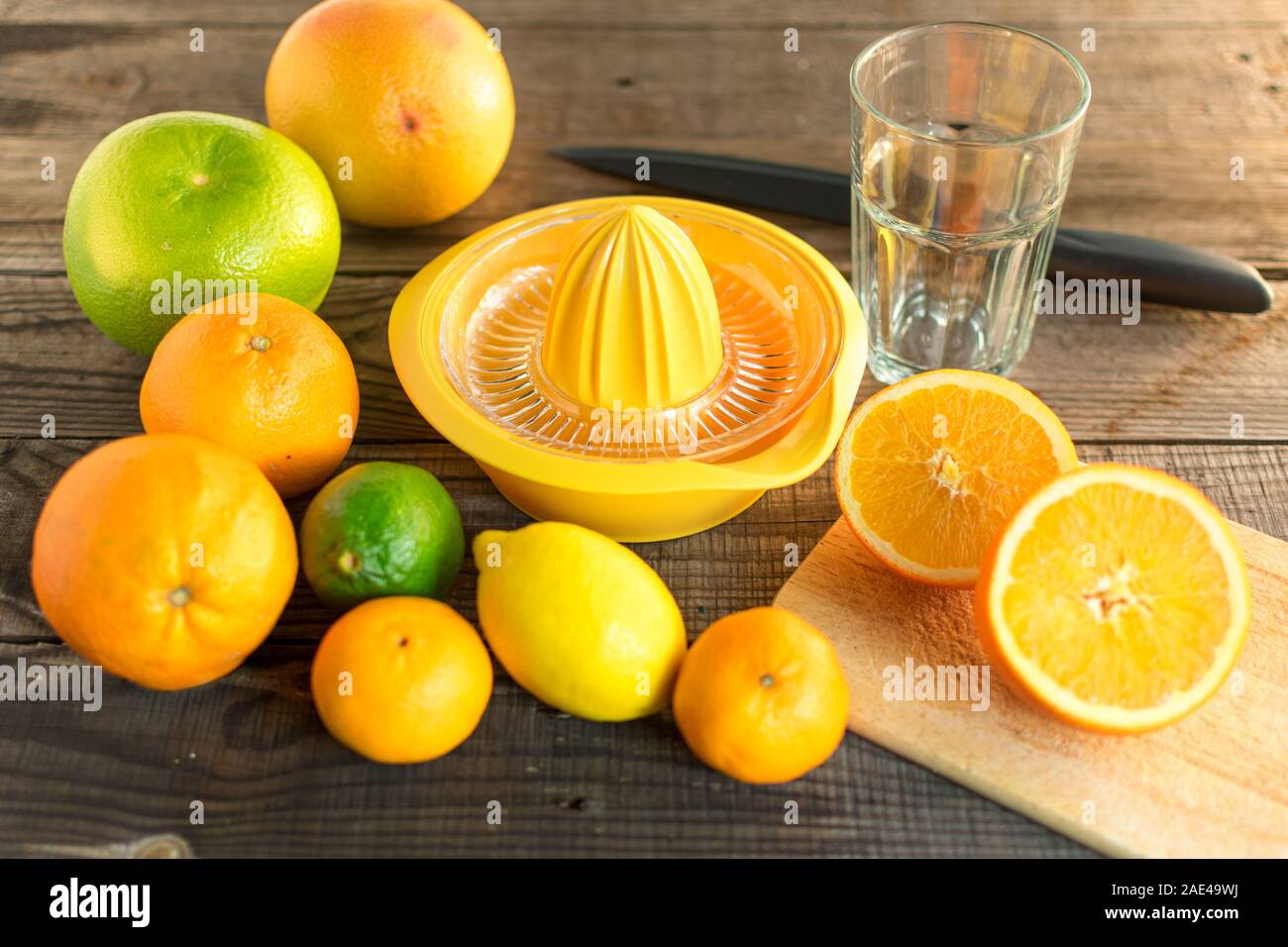 Moitié orange avec divers agrumes et centrifugeuse, planche à découper et couteau. Sur plancher en bois Banque D'Images Moitié orange avec divers agrumes et centrifugeuse, planche à découper et couteau. Sur plancher en bois Banque D'Images