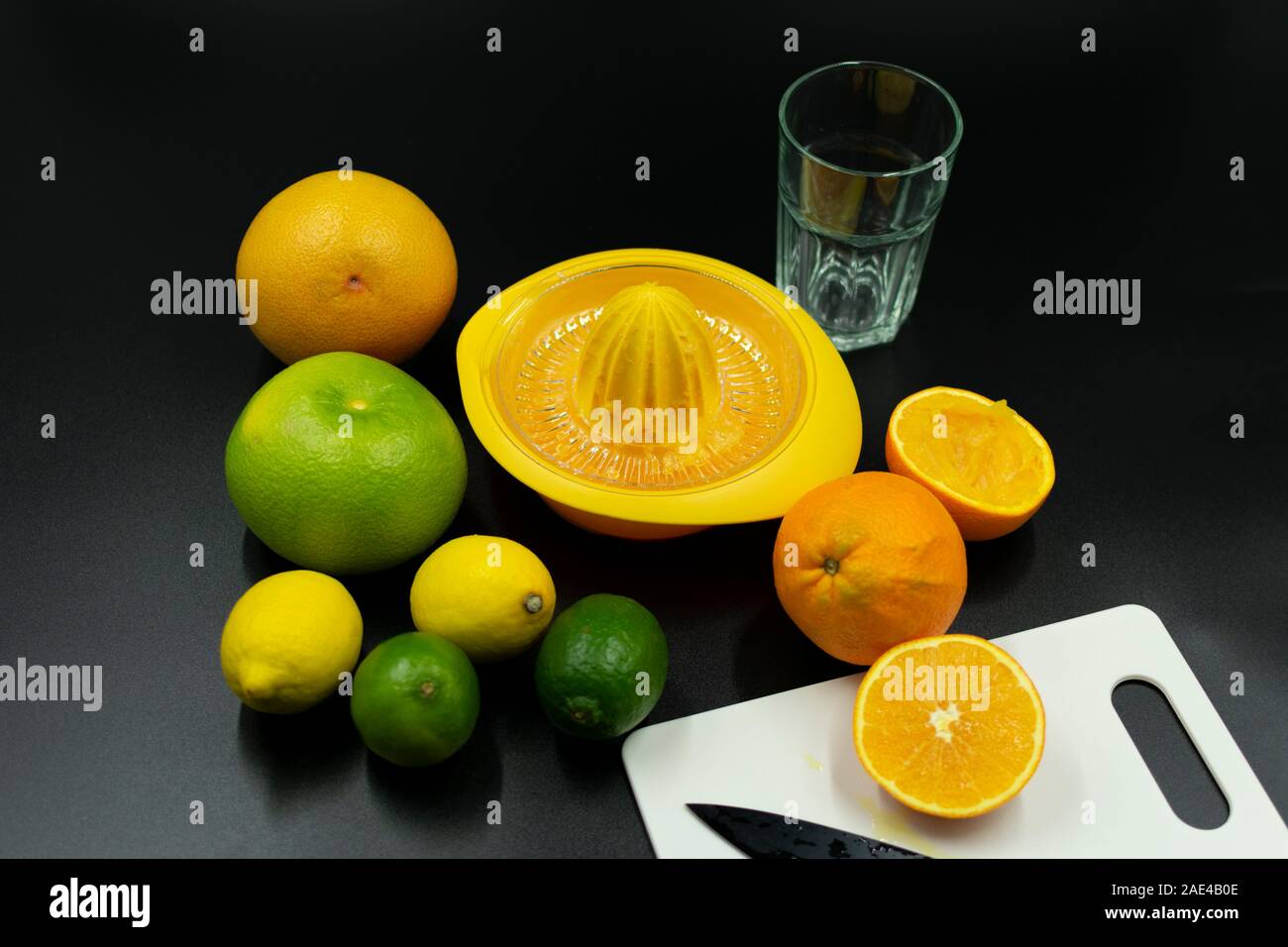 Utilisez un presse-agrumes de divers agrumes, de tranches d'orange et orange sur fond noir. Banque D'Images