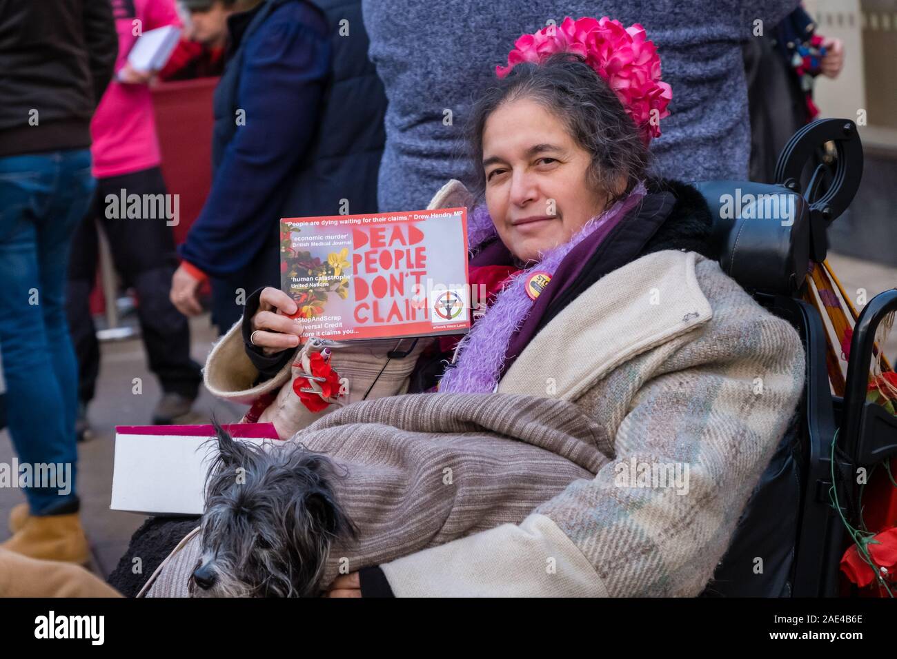 Londres, Royaume-Uni. 6e décembre 2019. Une femme dans un fauteuil roulant est titulaire d'une carte postale 'les gens ne font pas la réclamation" au théâtre de rue d'essai par les personnes à mobilité réduite contre les coupures (ATLC) dans le centre de Uxbridge appelant les électeurs à rejeter Boris Johnson et les conservateurs. Elles soulignent la environ 200 000 décès prématurés causés par des coupures et des sanctions, notamment l'élimination du Fonds de vie autonome, à crédit universel qui a entraîné une énorme augmentation de l'utilisation, comptoir alimentaire la faim chez les enfants, de la dette et les expulsions et un rapport de l'ONU de "violations graves et systématiques" des droits des personnes handicapées. Peter Marshall/Alamy Live News Banque D'Images
