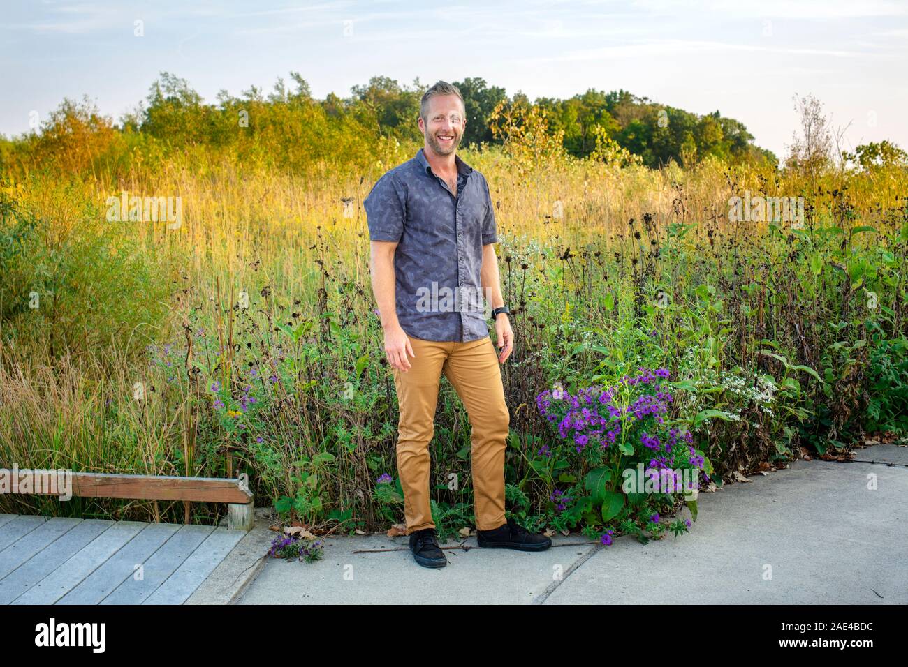 Un homme heureux est au bord d'une prairie remplie de fleurs de soleil Banque D'Images