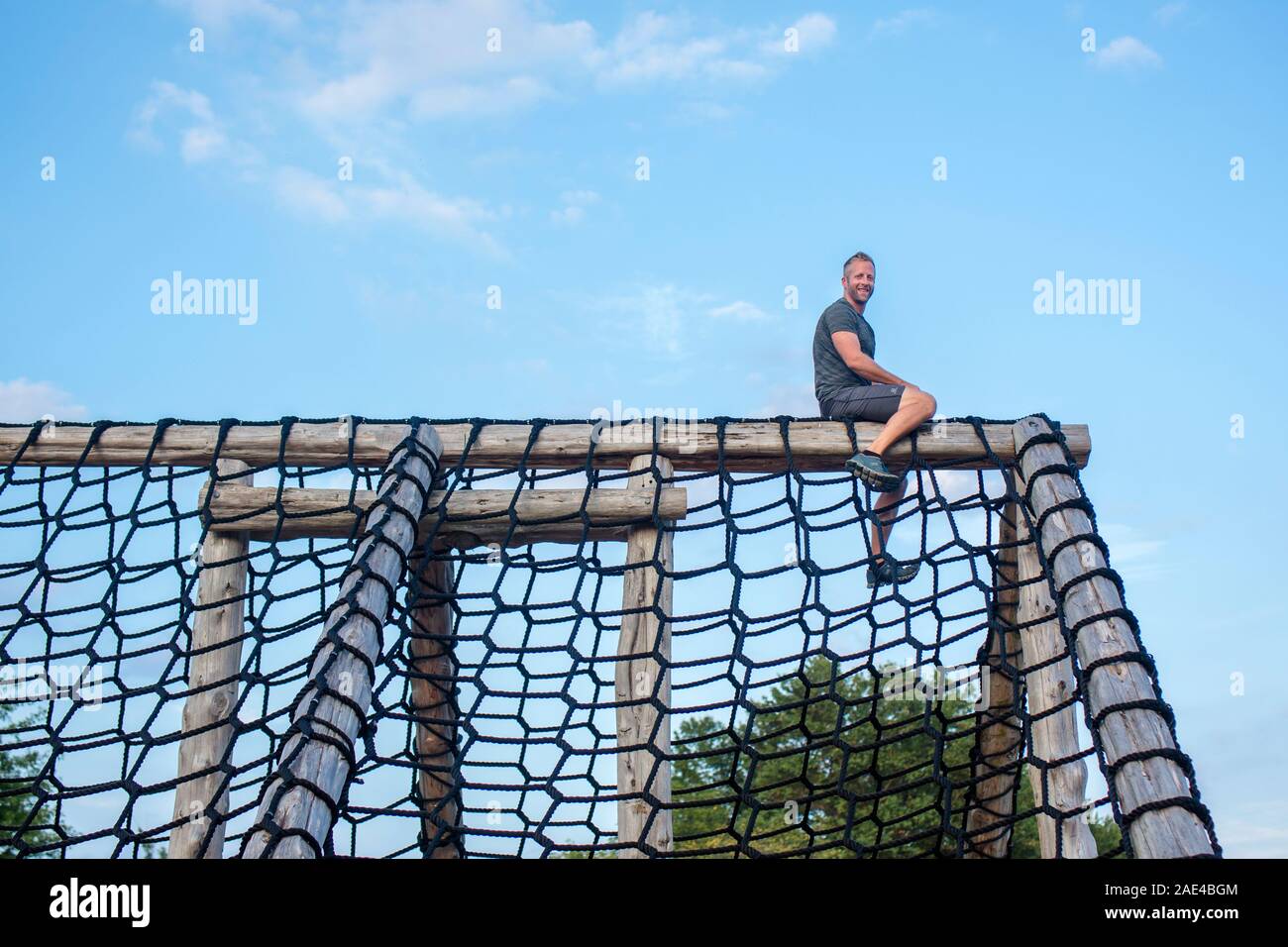 Au-dessous de l'homme assis à la haute fièrement au sommet d'une structure d'escalade corde Banque D'Images