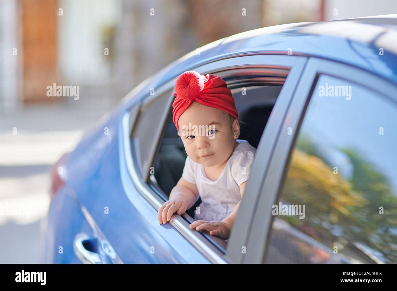 Mignon bébé fille arabe dans la fenêtre de voiture passe journée ensoleillée Banque D'Images