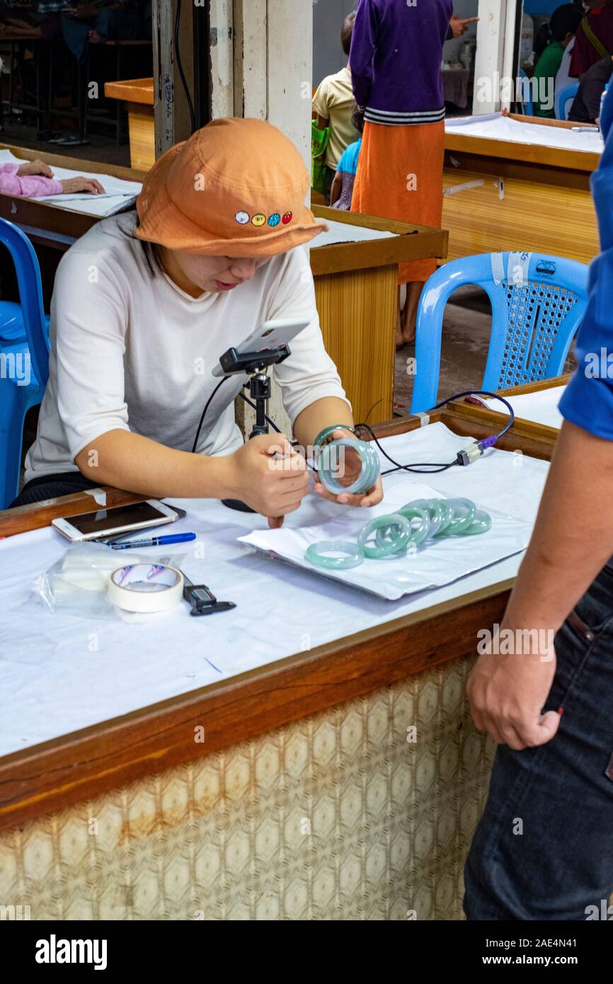 Un expert chinois femelle partage son évaluation des prix des bracelets de jade via téléphone mobile avec un acheteur en Chine dans le marché de jade de Mandalay Banque D'Images