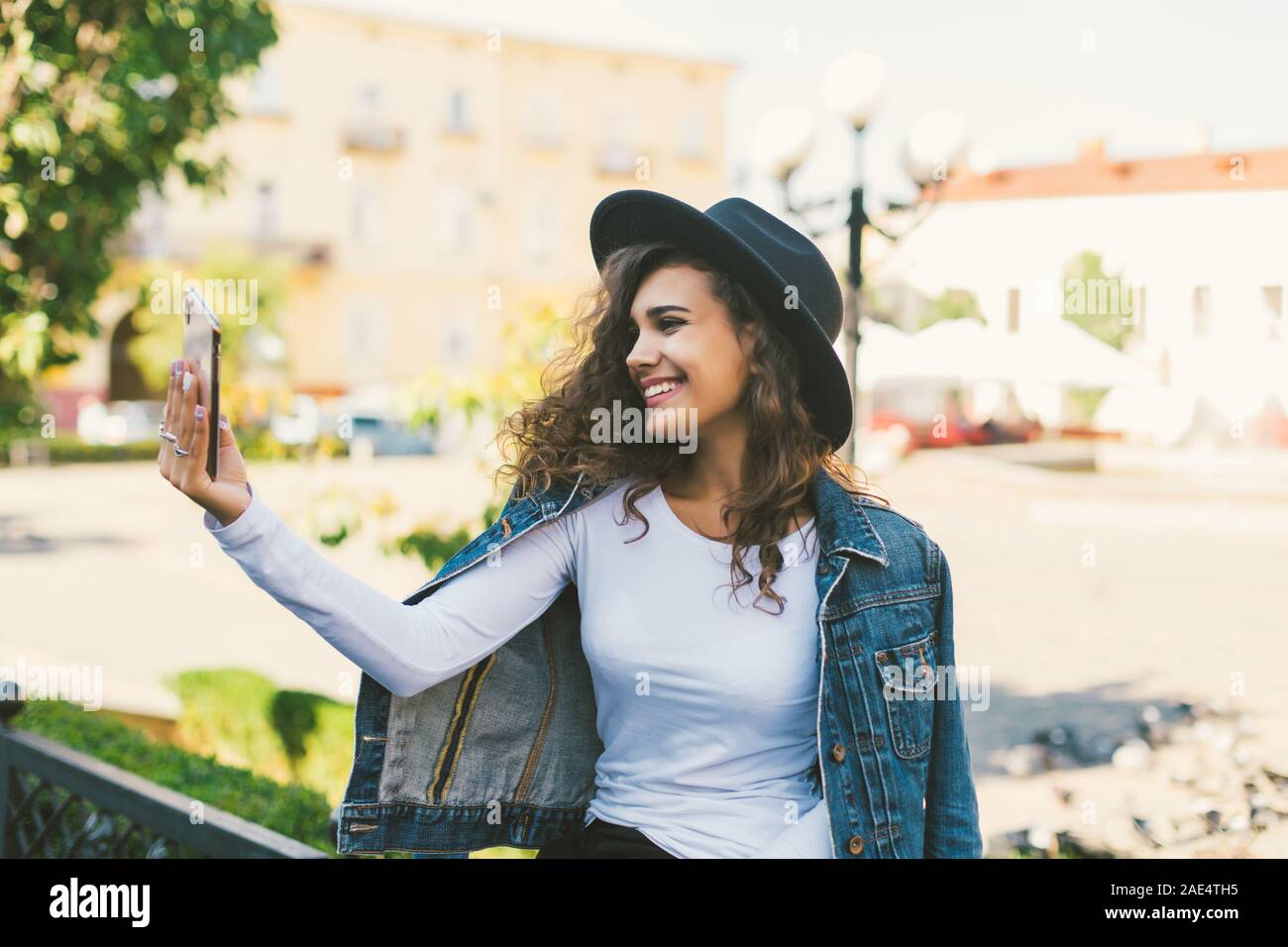 Jeune fille prendre des selfies mains avec téléphone sur summer city street. La vie urbaine concept. Banque D'Images