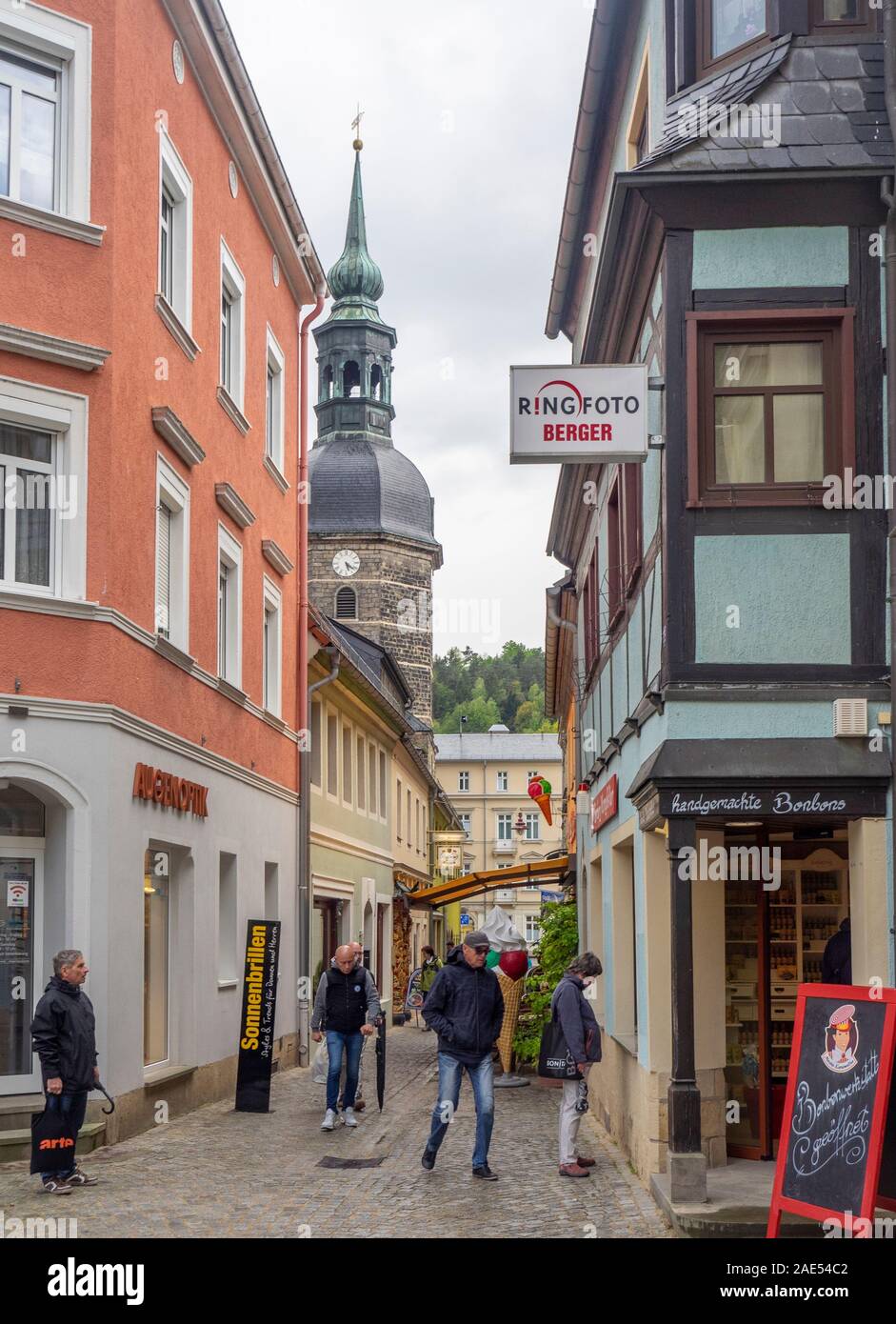 Les gens marchaient le long de la ruelle et de la tour d'horloge et de la spire de l'église Saint-Johannis dans la ville thermale Bad Schandau Saxe Allemagne. Banque D'Images Les gens marchaient le long de la ruelle et de la tour d'horloge et de la spire de l'église Saint-Johannis dans la ville thermale Bad Schandau Saxe Allemagne. Banque D'Images