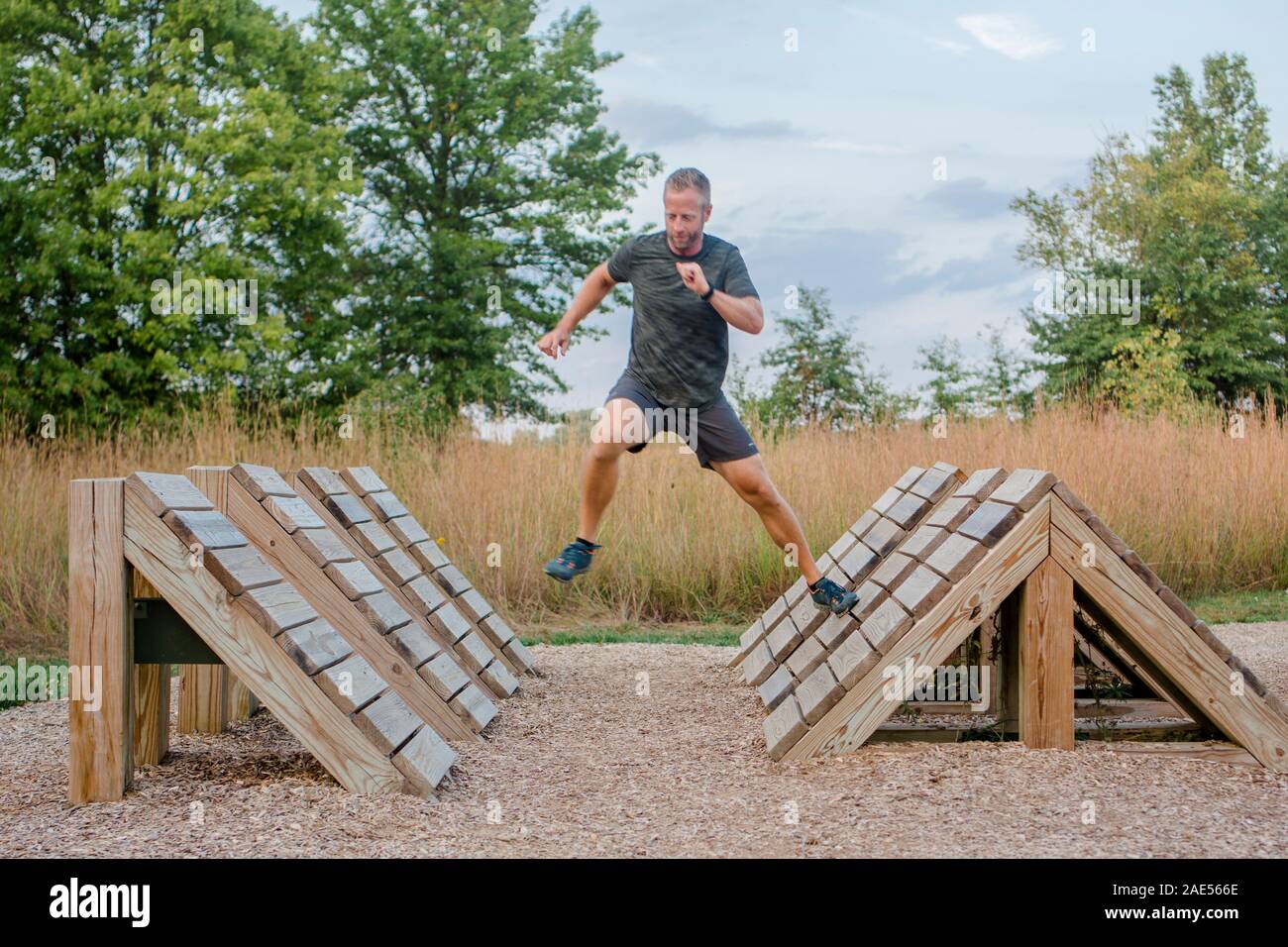 Mettre en place un homme court à travers des plates-formes en bois en course d'obstacles extérieure Banque D'Images