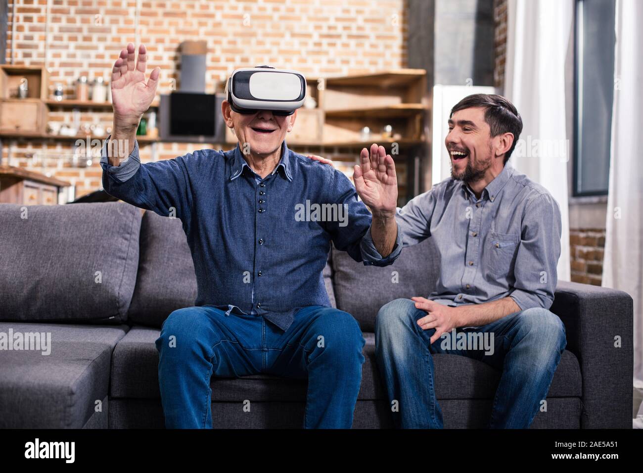 Un homme âgé à l'aide de périphériques VR avec son fils Banque D'Images