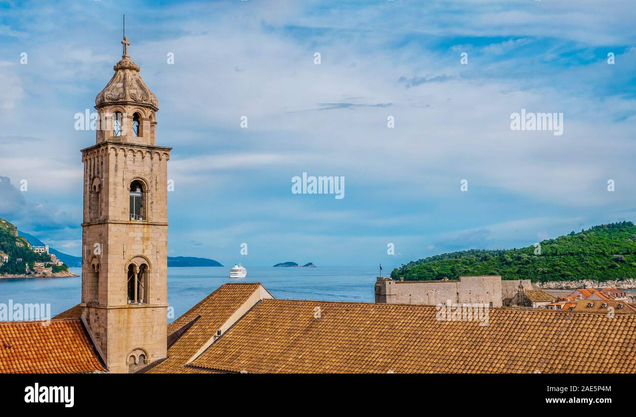 Se concentrer sur une cathédrale médiévale et clocher de tuiles orange à Dubrovnik, en Croatie, avec la mer et le littoral dans l'arrière-plan. Banque D'Images