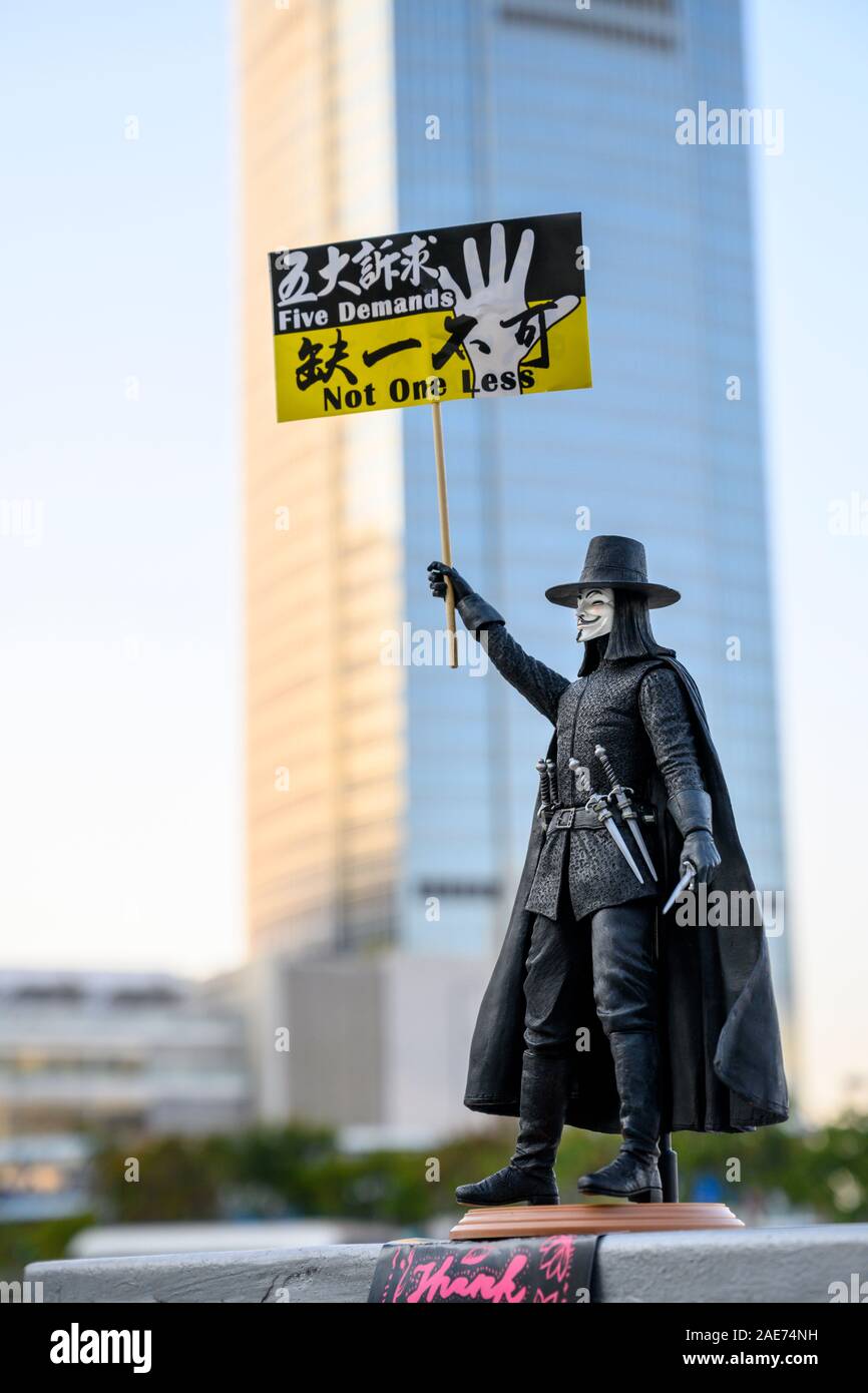 Un exemple de l'art de protestation de Hong Kong trouvé dans de nombreux médias de toute la ville. Une poupée de V de V pour Vendetta possède une bannière de protestation. Centre De Hong Kong 7 Décembre 2019, Banque D'Images