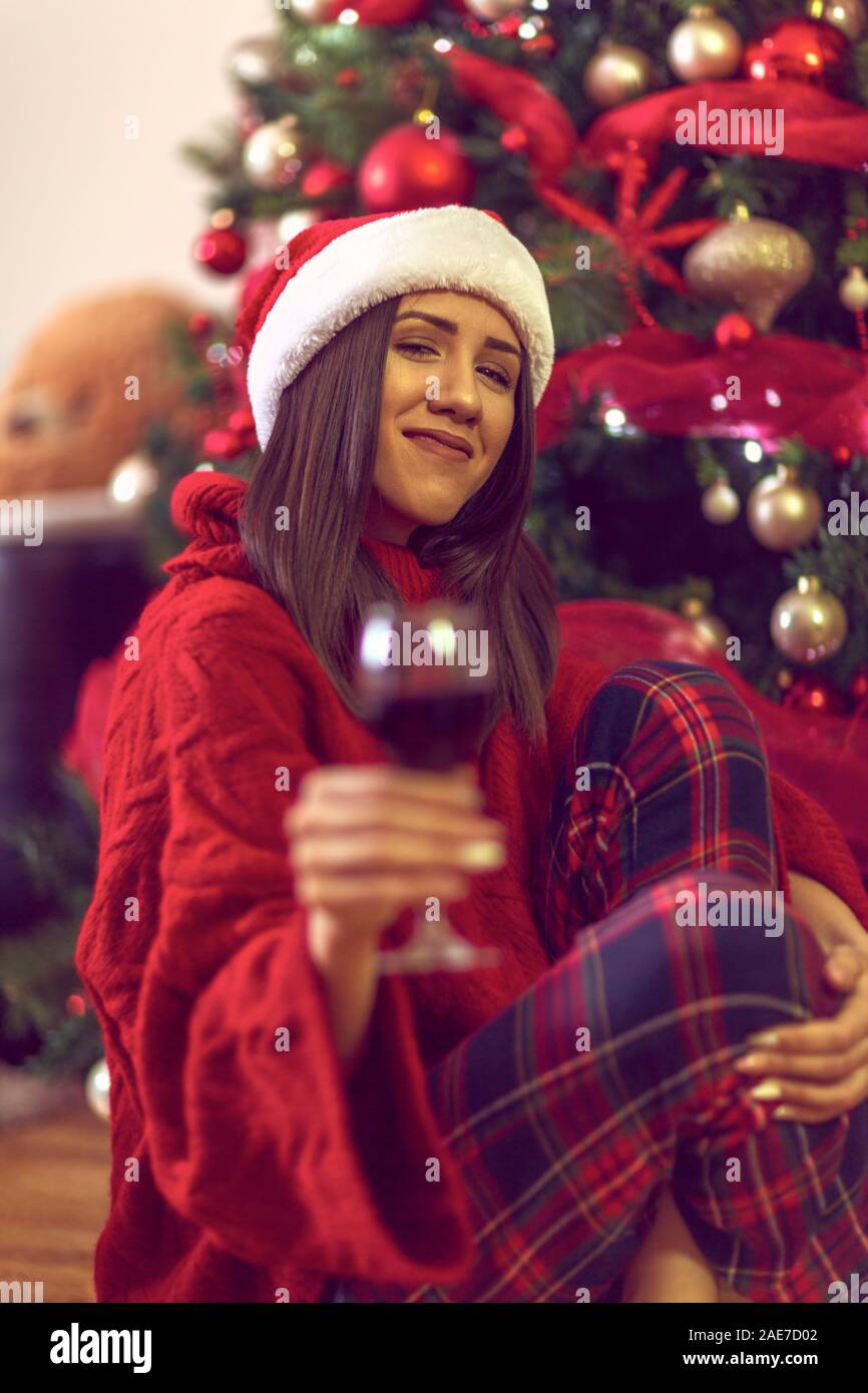 Noël et Nouvel An.Young Woman in Santa's hat est la tenue d'un verre de vin. Banque D'Images
