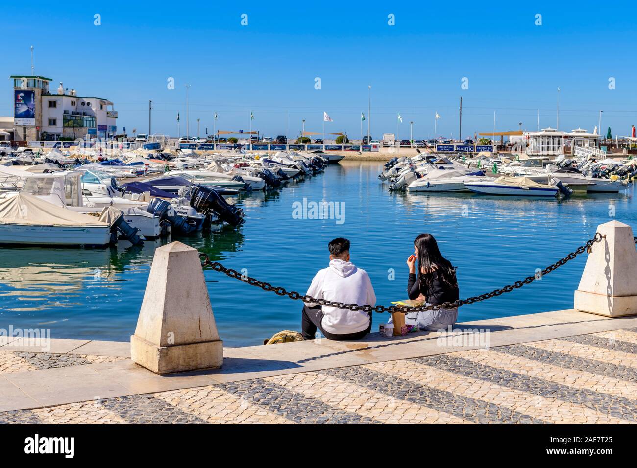 Jeune couple appréciant un déjeuner romantique en plein air dehors assis sur le quai à la marina de Faro, Algarve est Portugal. Banque D'Images