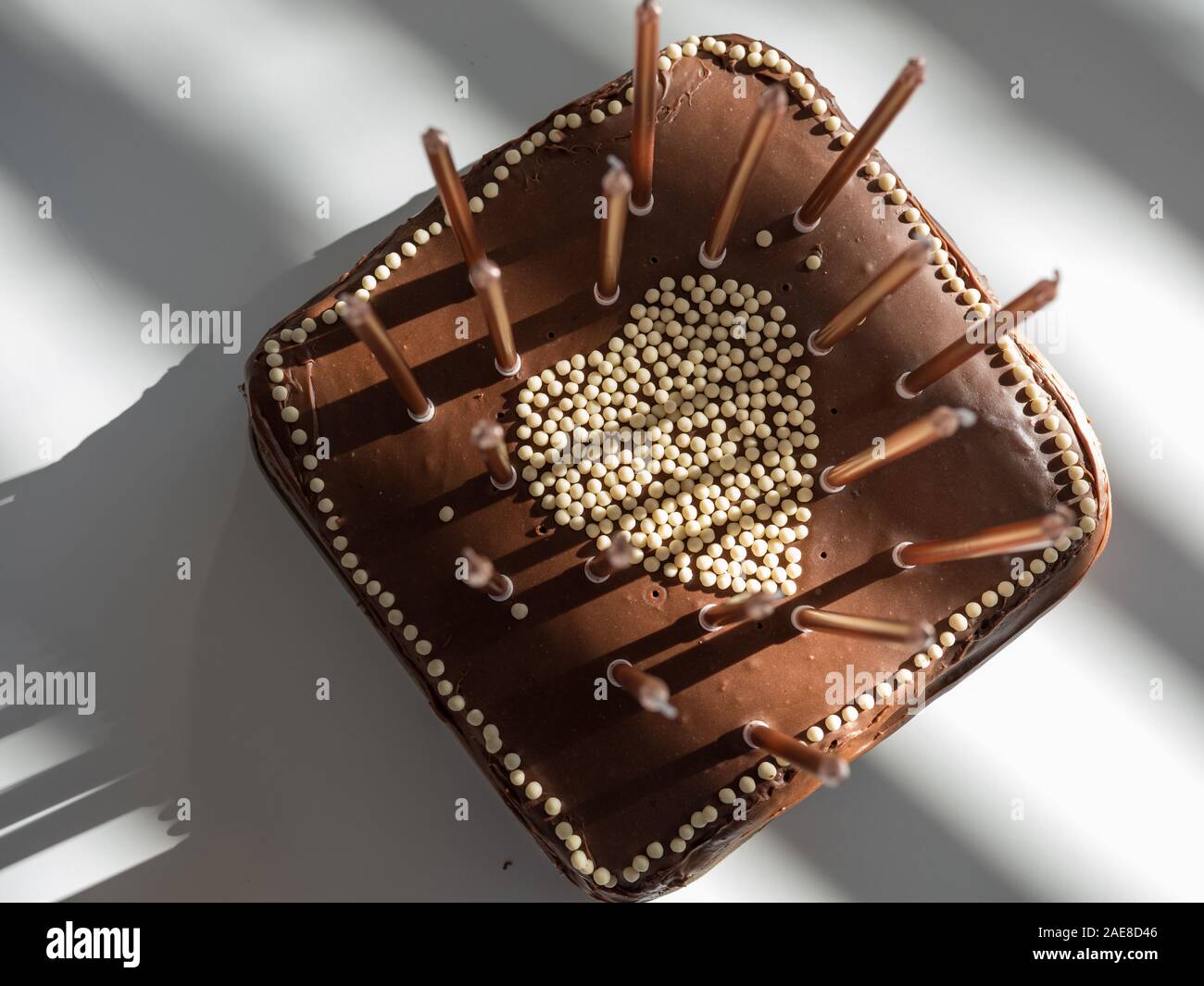 Beau gâteau au chocolat avec des bougies d'anniversaire et un coeur en forme de bonbons dans le milieu très haute résolution angle incroyable avec les ombres Banque D'Images