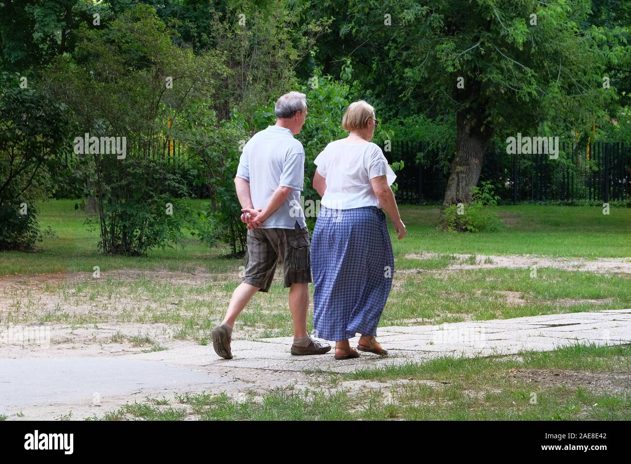 Couple de personnes âgées est la marche en vert le parc à jour de congé. Couple d'âge moyen est la marche. Les arbres verts sur les côtés du sentier. Banque D'Images