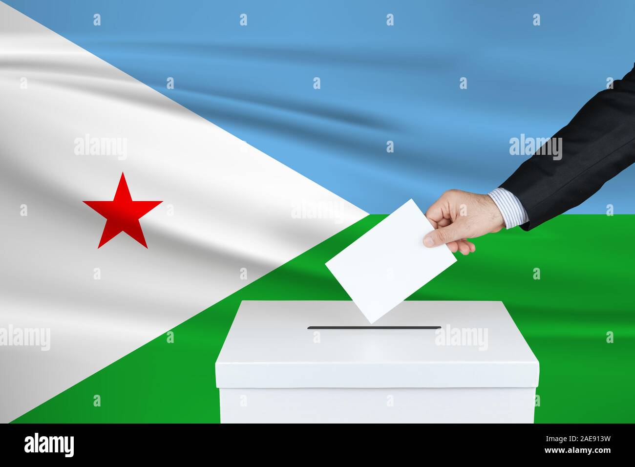 Élection à Djibouti. La main de l'homme qui a mis son vote dans l'urne. Drapeau de Djibouti ondulé sur fond. Banque D'Images