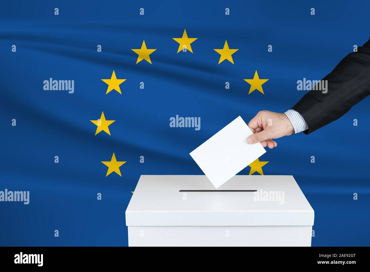 Élections dans l'Union européenne. La main de l'homme qui a mis son vote dans l'urne. Drapeau de l'Union européenne ondulé sur fond. Banque D'Images