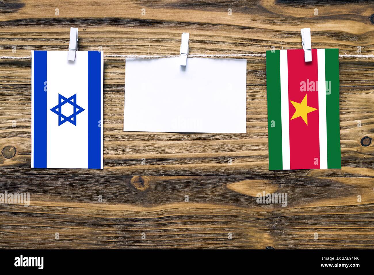 Drapeaux suspendus d'Israël et le Suriname attaché à corde avec pinces à linge avec de l'espace de copie sur papier blanc sur fond de bois.Les relations diplomatiques Banque D'Images