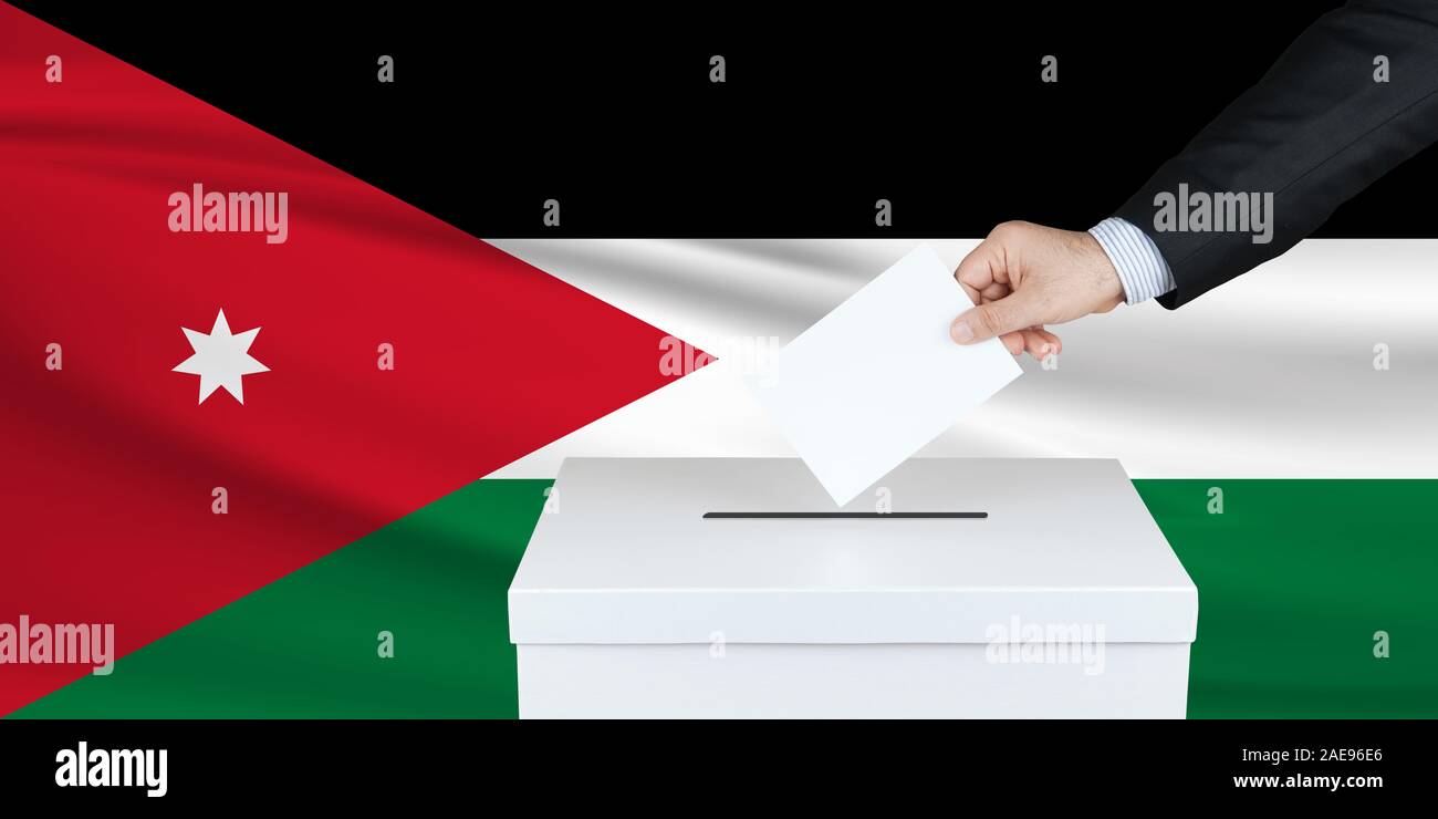 Élections en Jordanie. La main de l'homme qui a mis son vote dans l'urne. Drapeau Jordan ondulé sur fond. Banque D'Images