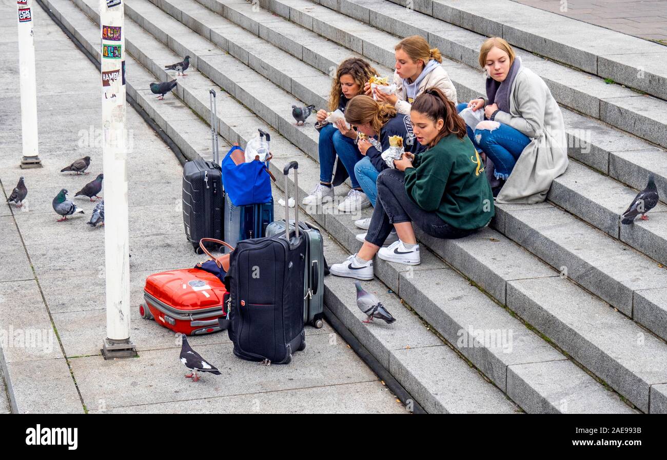 Cinq femmes de touristes avec des bagages manger prendre la nourriture sur les escaliers de l'Alster sur le front de mer de Kleine Alster Altstadt Hambourg Allemagne Banque D'Images