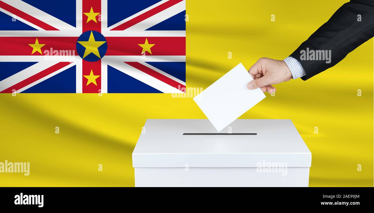 Élection à Nioué. La main de l'homme qui a mis son vote dans l'urne. Drapeau Niue ondulé sur fond. Banque D'Images