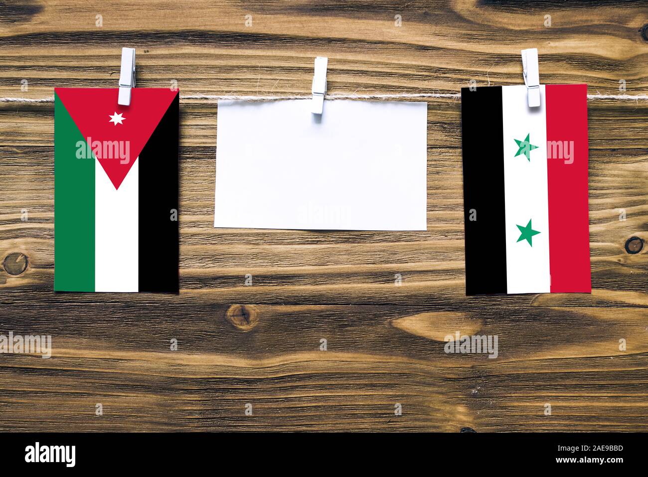 Drapeaux suspendus de Jordanie et Syrie attaché à corde avec pinces à linge avec de l'espace de copie sur papier blanc sur fond de bois.Les relations diplomatiques bet Banque D'Images