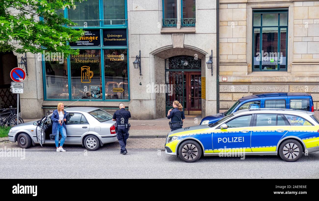 Les policiers et les policiers arrêtent un conducteur féminin pour une infraction à la circulation à Altstadt Hambourg, Allemagne. Banque D'Images