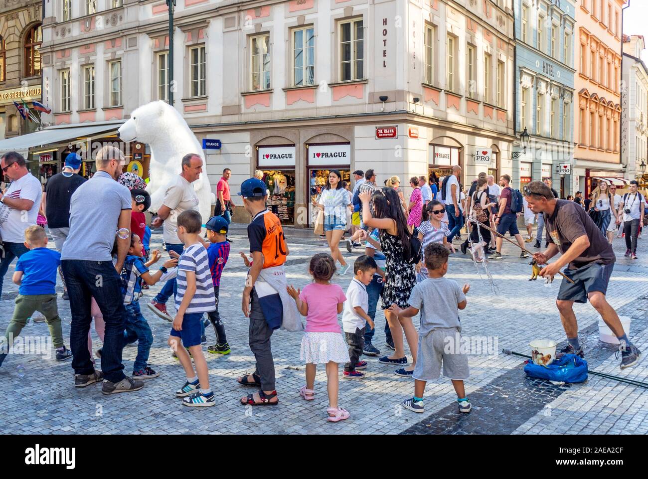 Homme faisant des bulles et des enfants tentant de capturer les bulles et le costume d'ours polaire dans la vieille ville de Prague, République tchèque. Banque D'Images