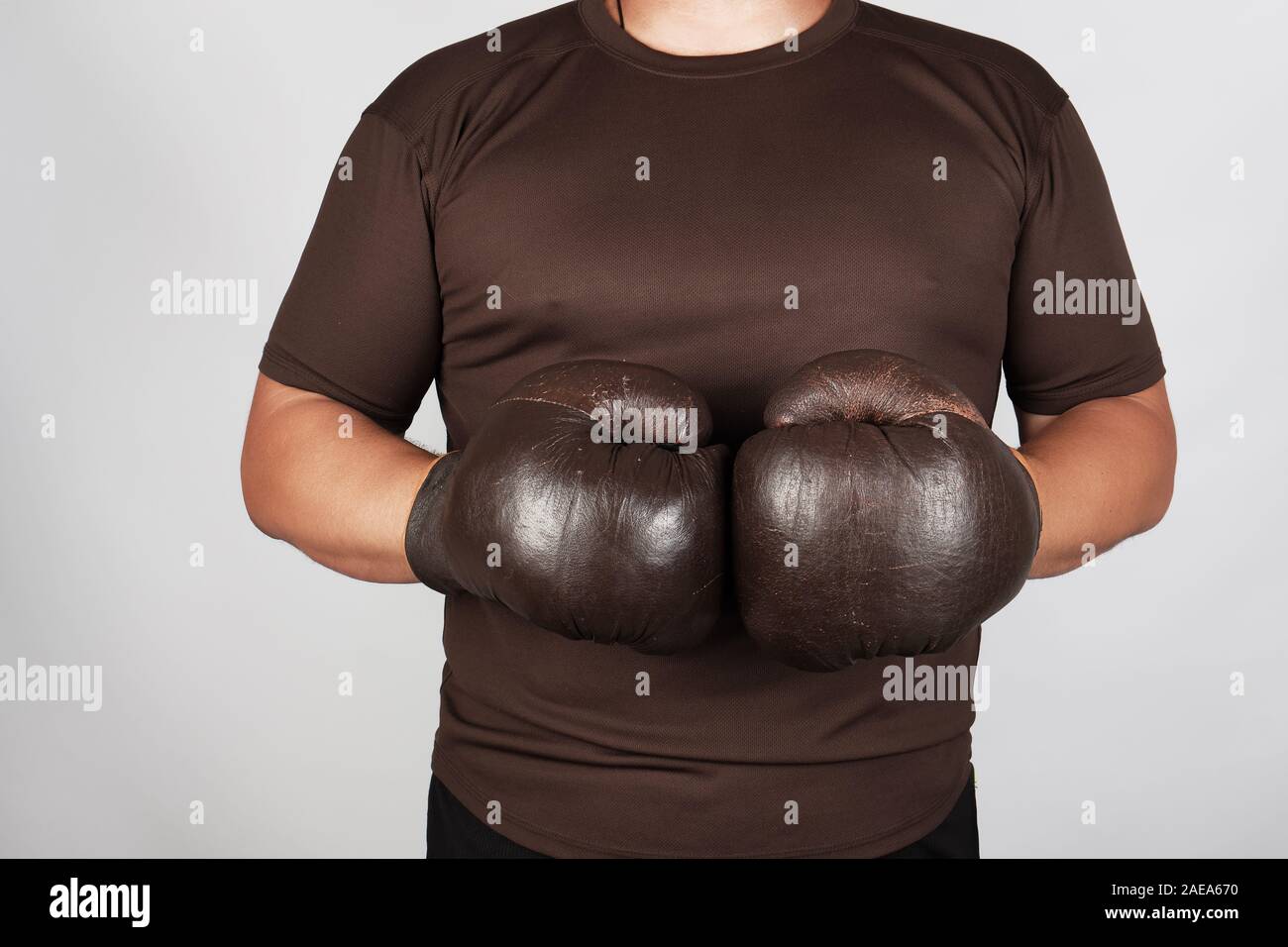 L'homme se tient en tenue très old vintage brown des gants de boxe sur ses mains, fond blanc Banque D'Images