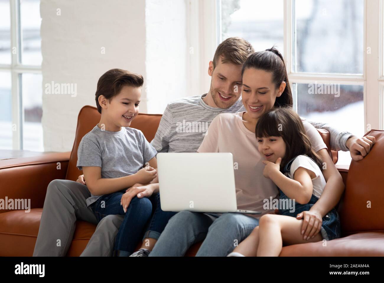 Heureux parents avec petite fille et fils à l'aide d'ordinateur portable. Banque D'Images