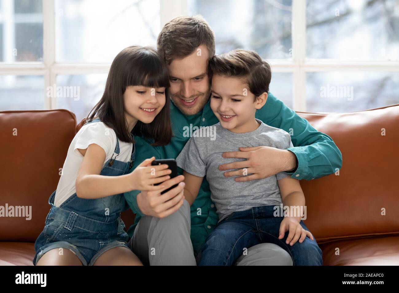 Père aimant permet à l'aide d'enfants avec selfies smartphone. Banque D'Images