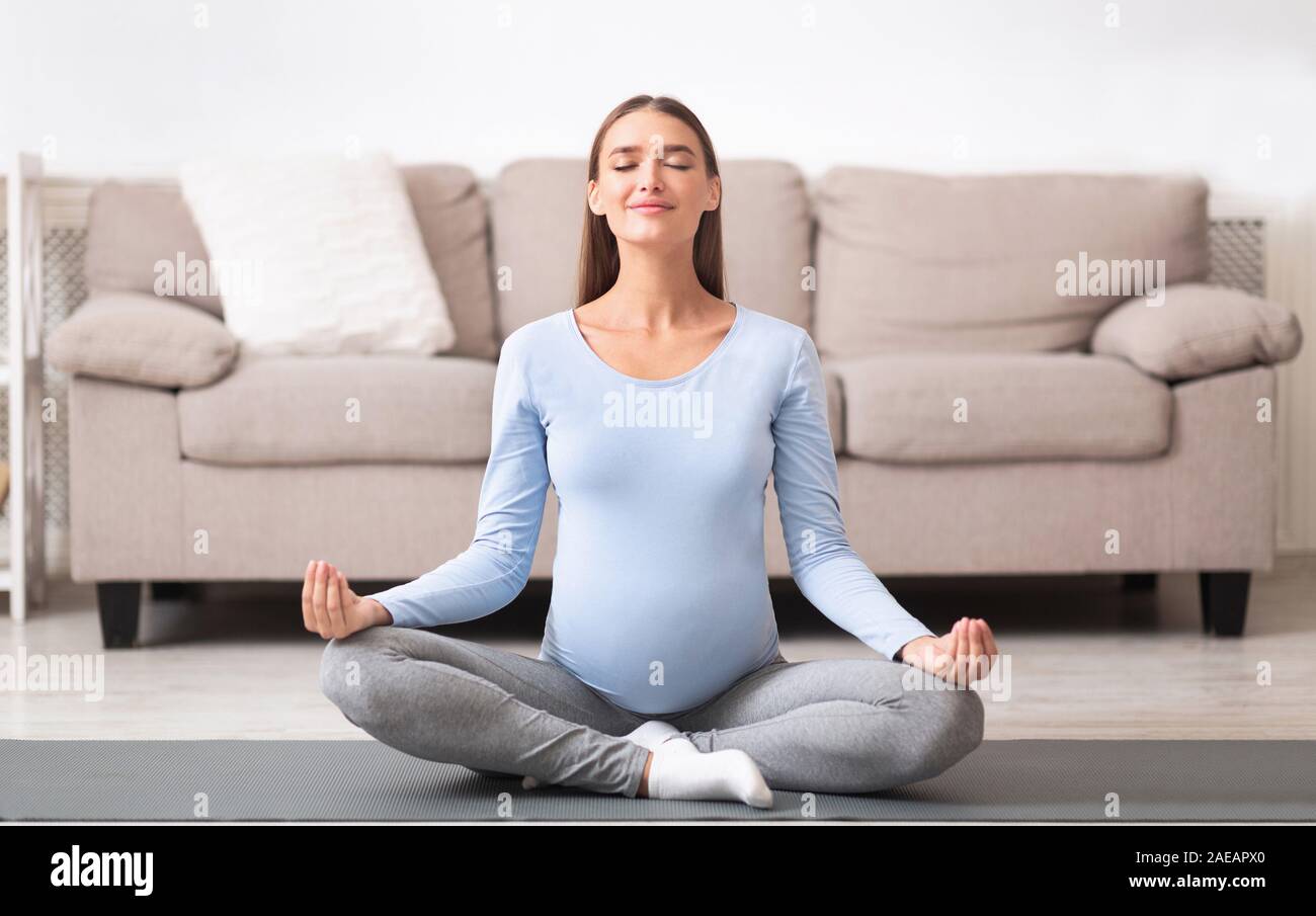 Les jeunes femmes enceintes détendue meditating on yoga mat Banque D'Images