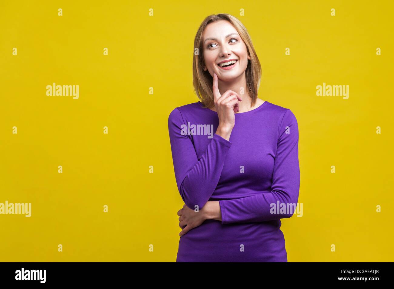 Portrait de femme adorable robe violette en main et toucher le visage, avoir une grande idée, à la pensée de côté plus de solution. je Banque D'Images