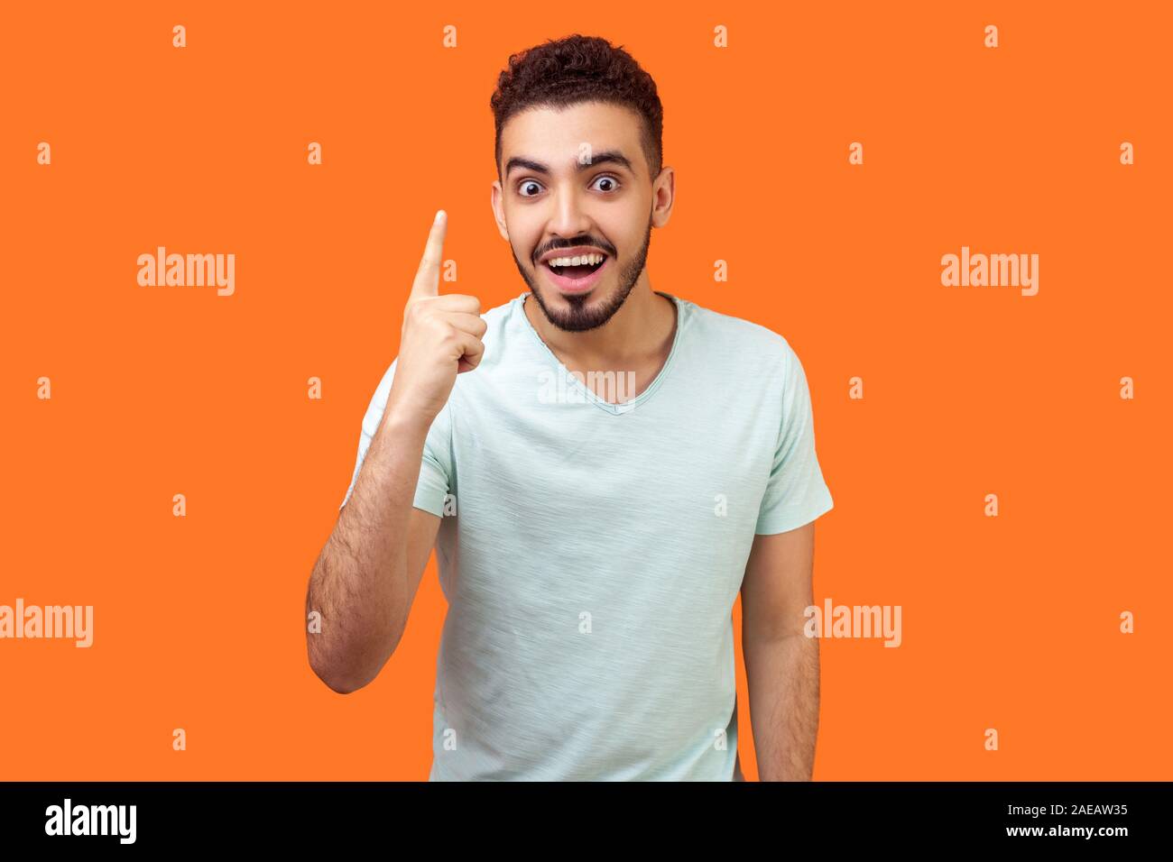 Portrait de l'homme inspiré beau brunette avec barbe en t-shirt blanc montre de l'index et à la recherche sur l'idée d'étonnement soudain, s'solution. je Banque D'Images