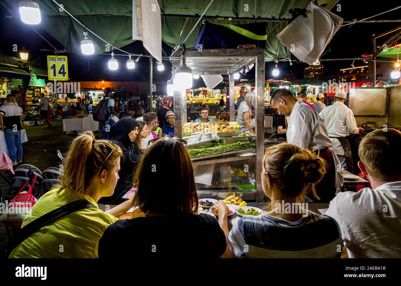 Les touristes profiter le repas autour de la longue table à tréteaux,dans la nuit dans la place Jemaa el-Fnaa ou place Djema el-Fna place du marché.Médina de Marrakech,Maroc Banque D'Images