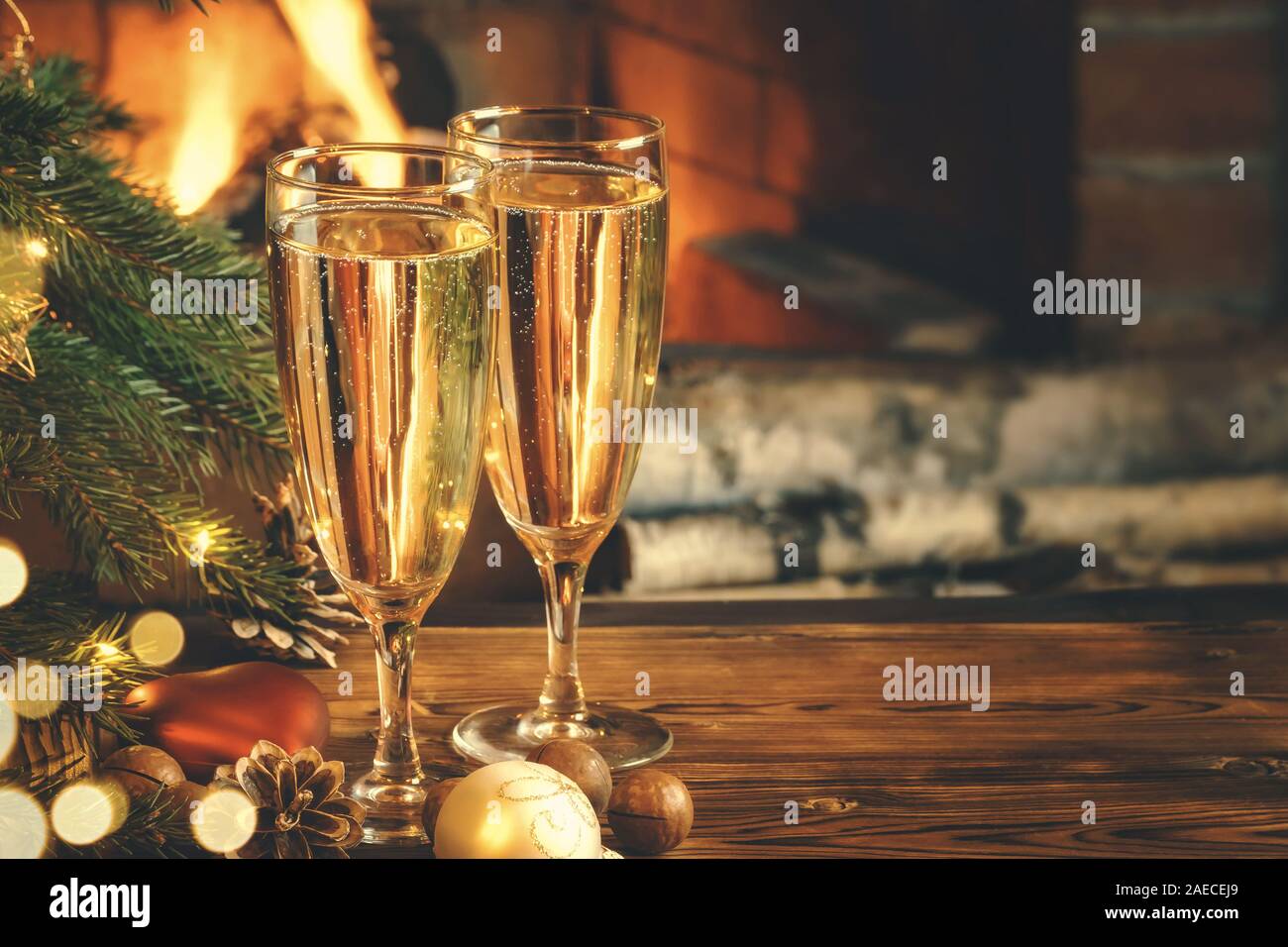 Composition de Noël - deux verres de champagne sur une table en bois près d'un arbre de Noël dans une chambre avec une cheminée. Banque D'Images