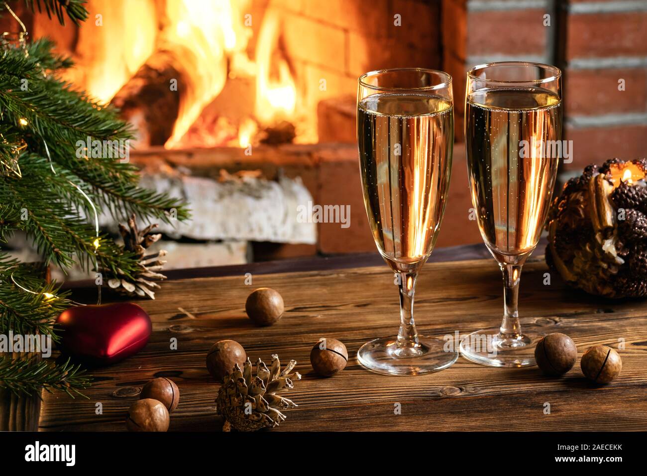 Composition de Noël - deux verres de champagne sur une table en bois près d'un arbre de Noël dans une chambre avec une cheminée. Banque D'Images