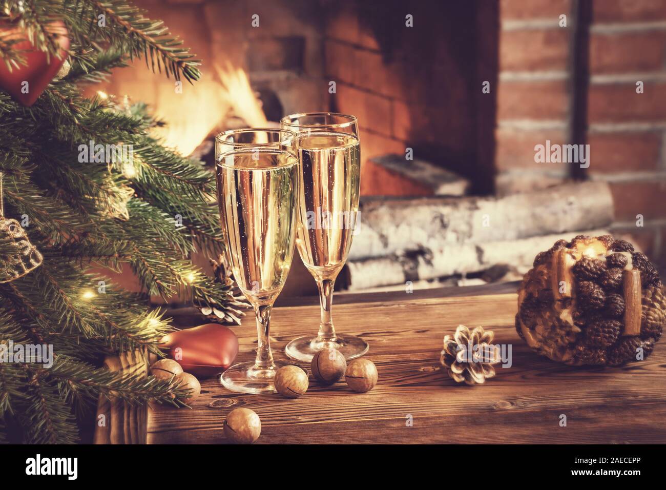 Composition de Noël - deux verres de champagne sur une table en bois près d'un arbre de Noël dans une chambre avec une cheminée. Banque D'Images